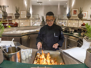 Küchenchef im Maritim proArte Hotel Berlin flambiert Speisen an der Live-Cooking-Station vor den Gästen.