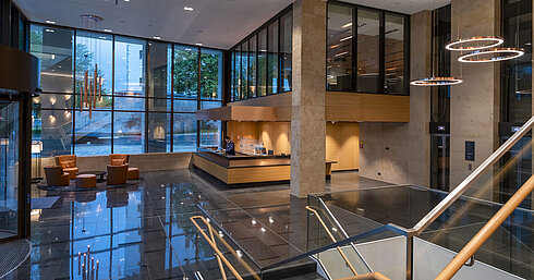 Die moderne Lobby des Maritim Hotel Ingolstadt mit hohen Glasfenstern, Rezeption und gemütlichen Sitzbereichen.