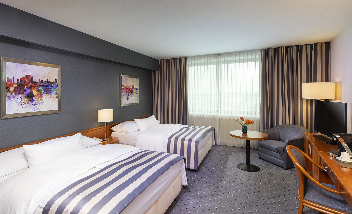 Familienzimmer im Maritim Hotel Ulm mit zwei Einzelbetten, TV und gemütlicher Sitzecke