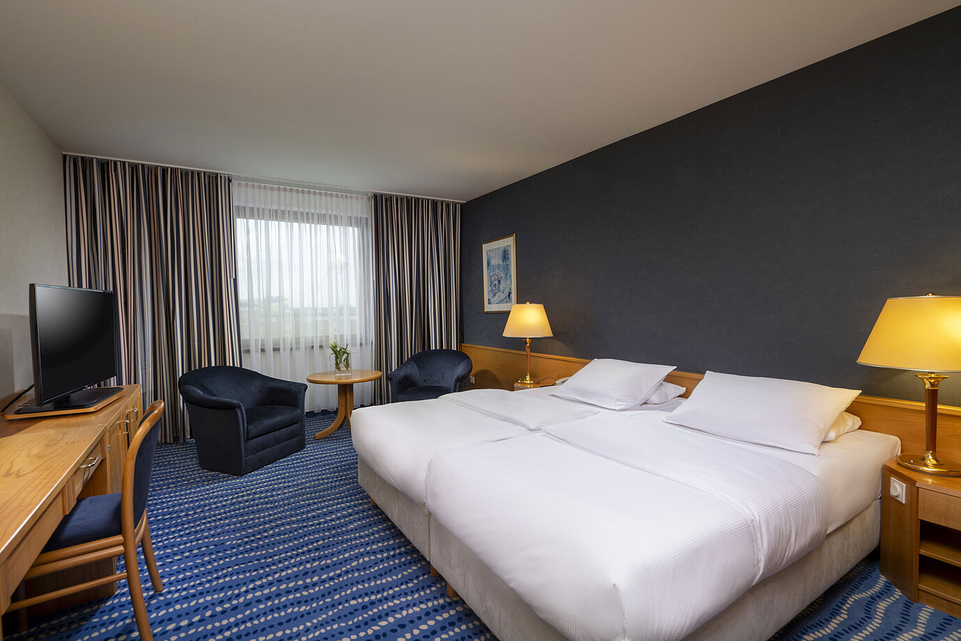 Comfort-Doppelzimmer mit Sitzbereich, Schreibtisch und modernen Kunstwerken an der Wand