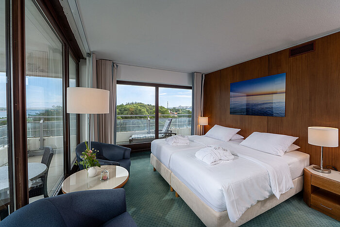 SuperiorPlus Zimmer Seeseite mit Doppelbett, Sitzecke und Blick auf die Ostsee und ins Grüne