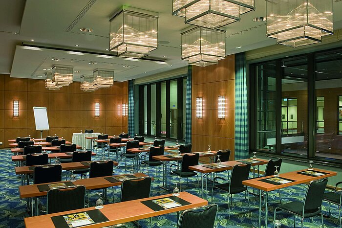 Moderner Konferenzraum mit eleganten Kronleuchtern, Holzwänden und großen Fensterfronten im Maritim Hotel