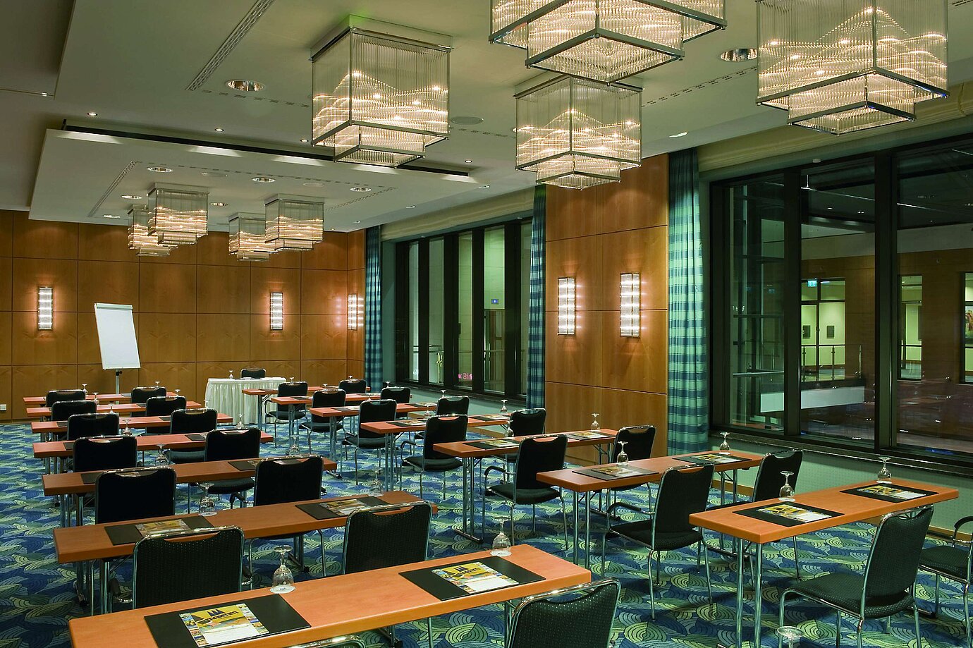 Moderner Konferenzraum mit eleganten Kronleuchtern, Holzwänden und großen Fensterfronten im Maritim Hotel