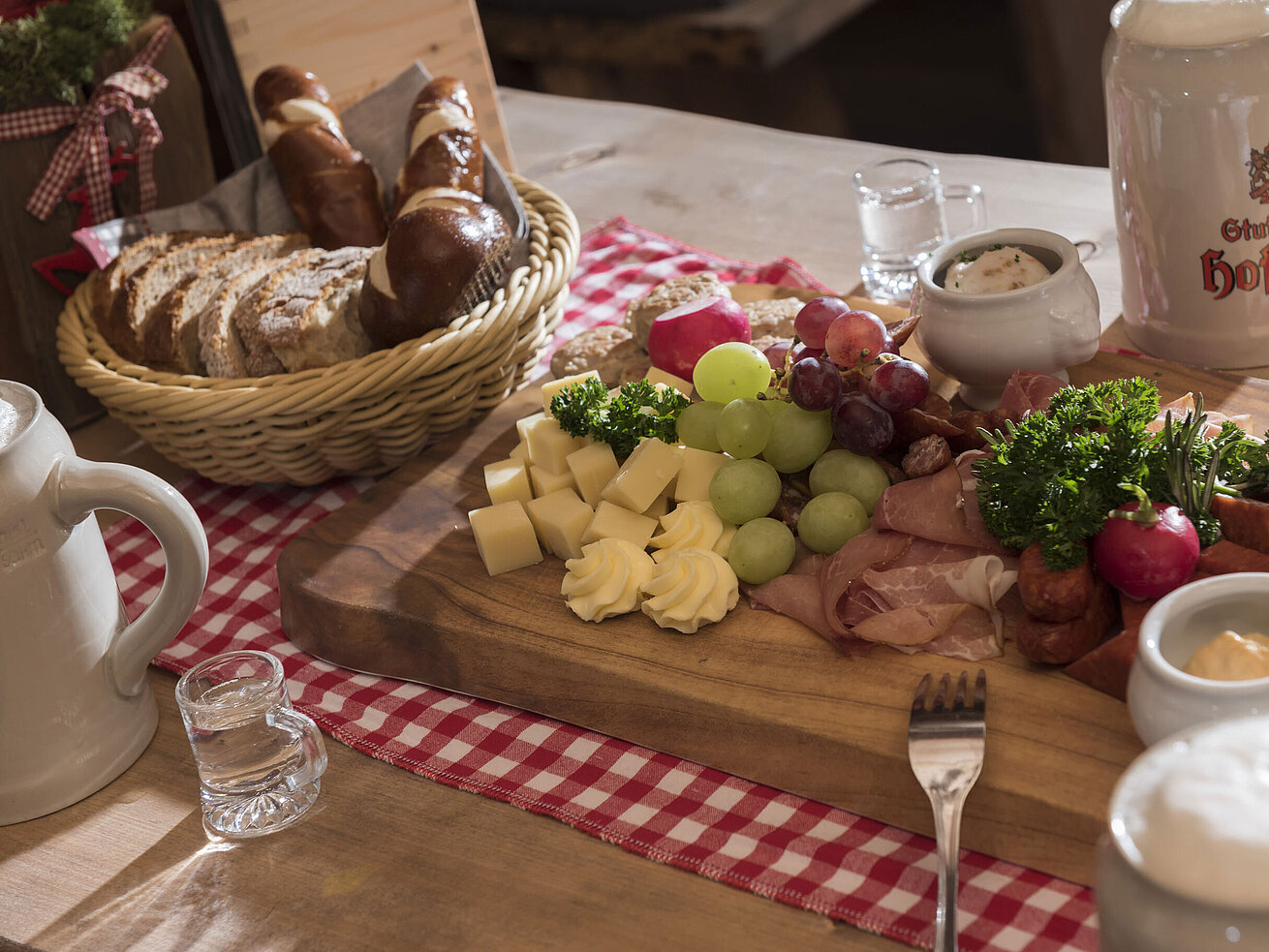 *Rustikale Brotzeit mit Käse, Wurst, Trauben, Brezen und Bierkrug in der ElbAlm