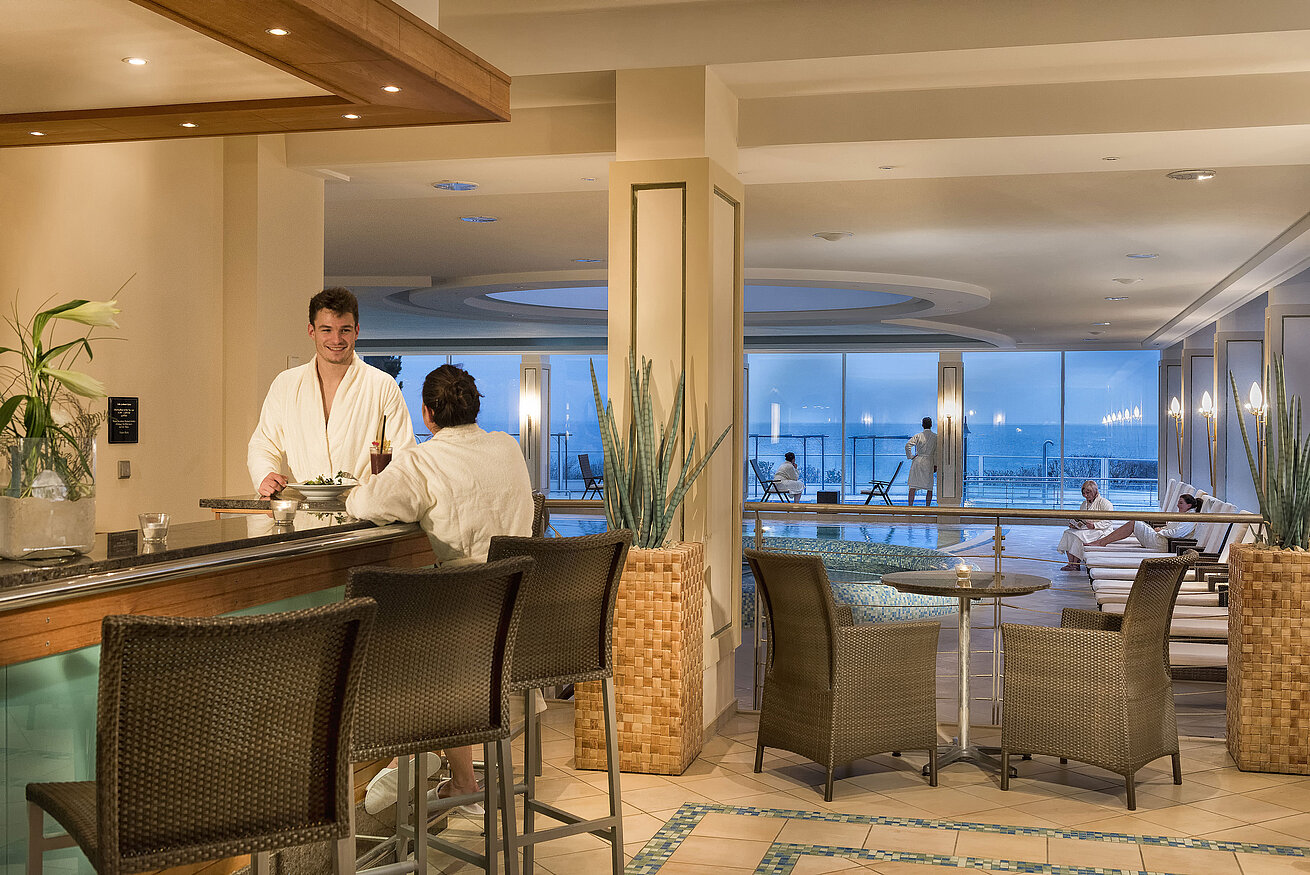 Wellnessbereich mit Pool und Gästen in Bademänteln im Maritim Seehotel Timmendorfer Strand.