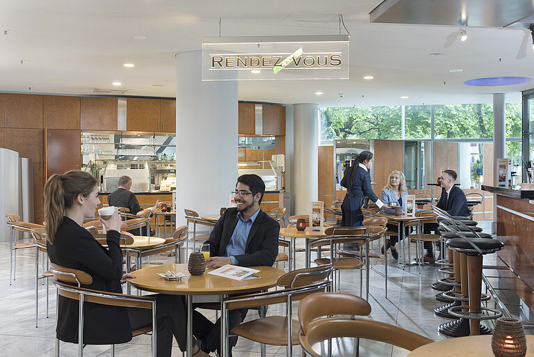 Das Café Rendezvous im Maritim Hotel Frankfurt mit Gästen, die Kaffee genießen, und freundlichem Servicepersonal.
