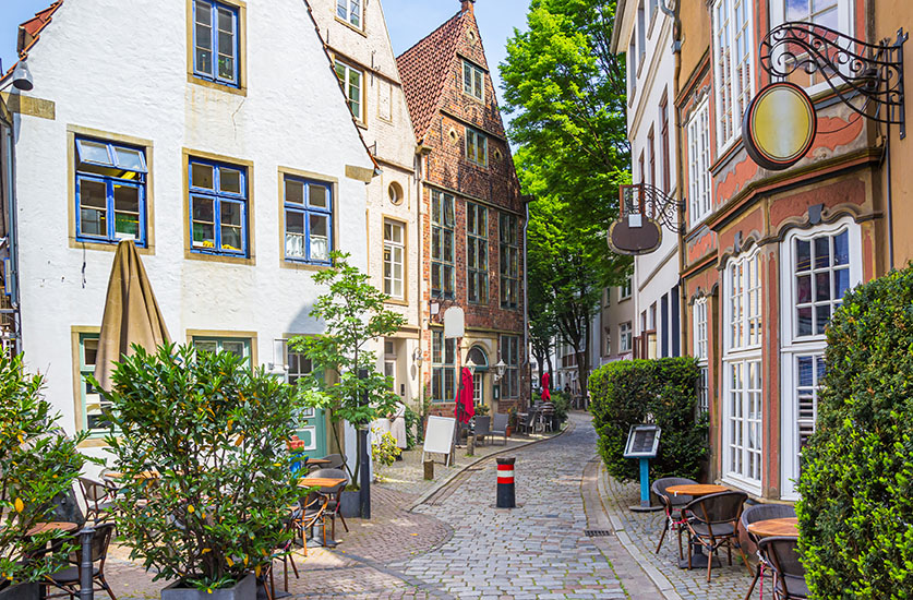 © venemama - AdobeStock.com Historische Gasse im Schnoorviertel in Bremen mit alten Häusern, Kopfsteinpflaster und grüner Bepflanzung