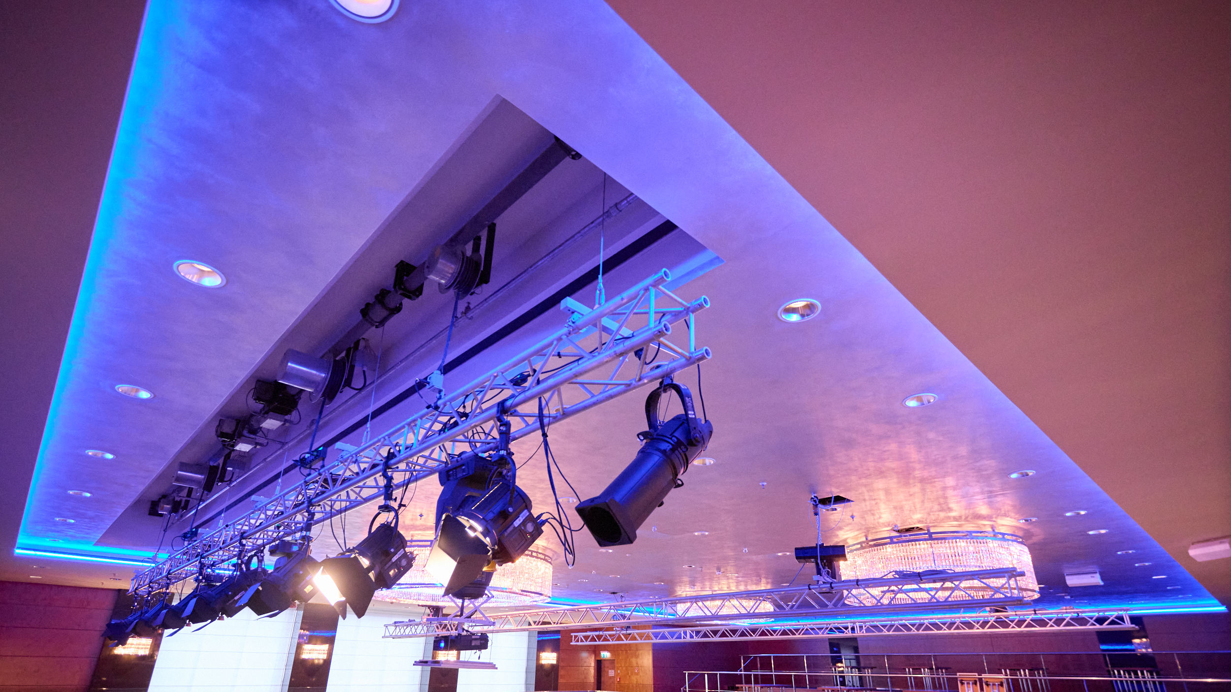 Deckenmontierte Licht- und Bühnentechnik in einem modern beleuchteten Veranstaltungsraum.