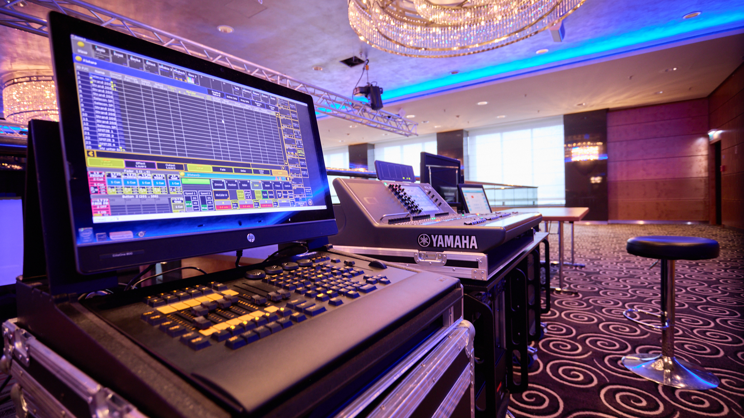 Professionelles Licht- und Mischpult in einem modern ausgestatteten Veranstaltungsraum mit Bühne.