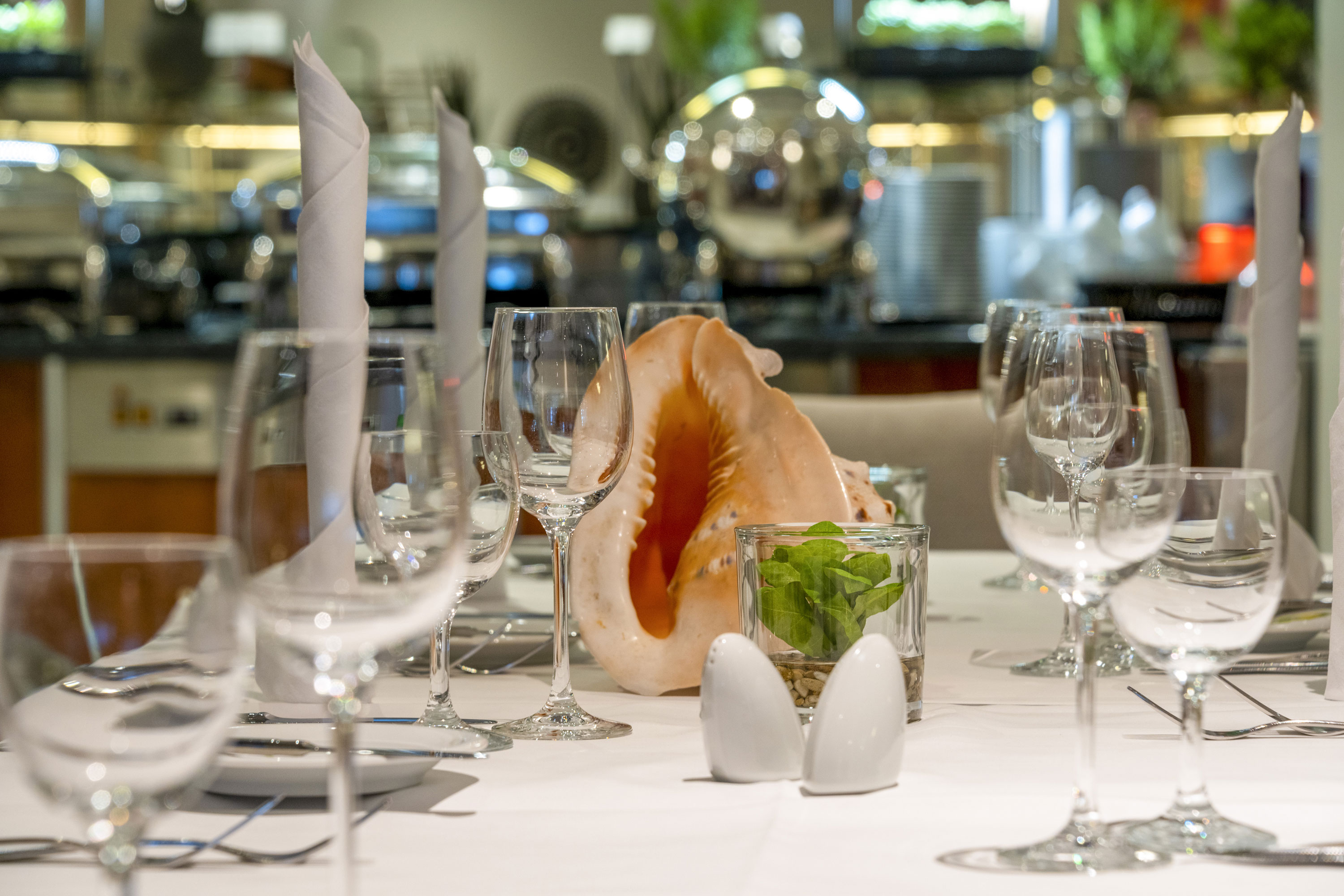 Elegant gedeckter Tisch im Maritim proArte Hotel Berlin mit dekorativer Muschel und Glas-Arrangement.