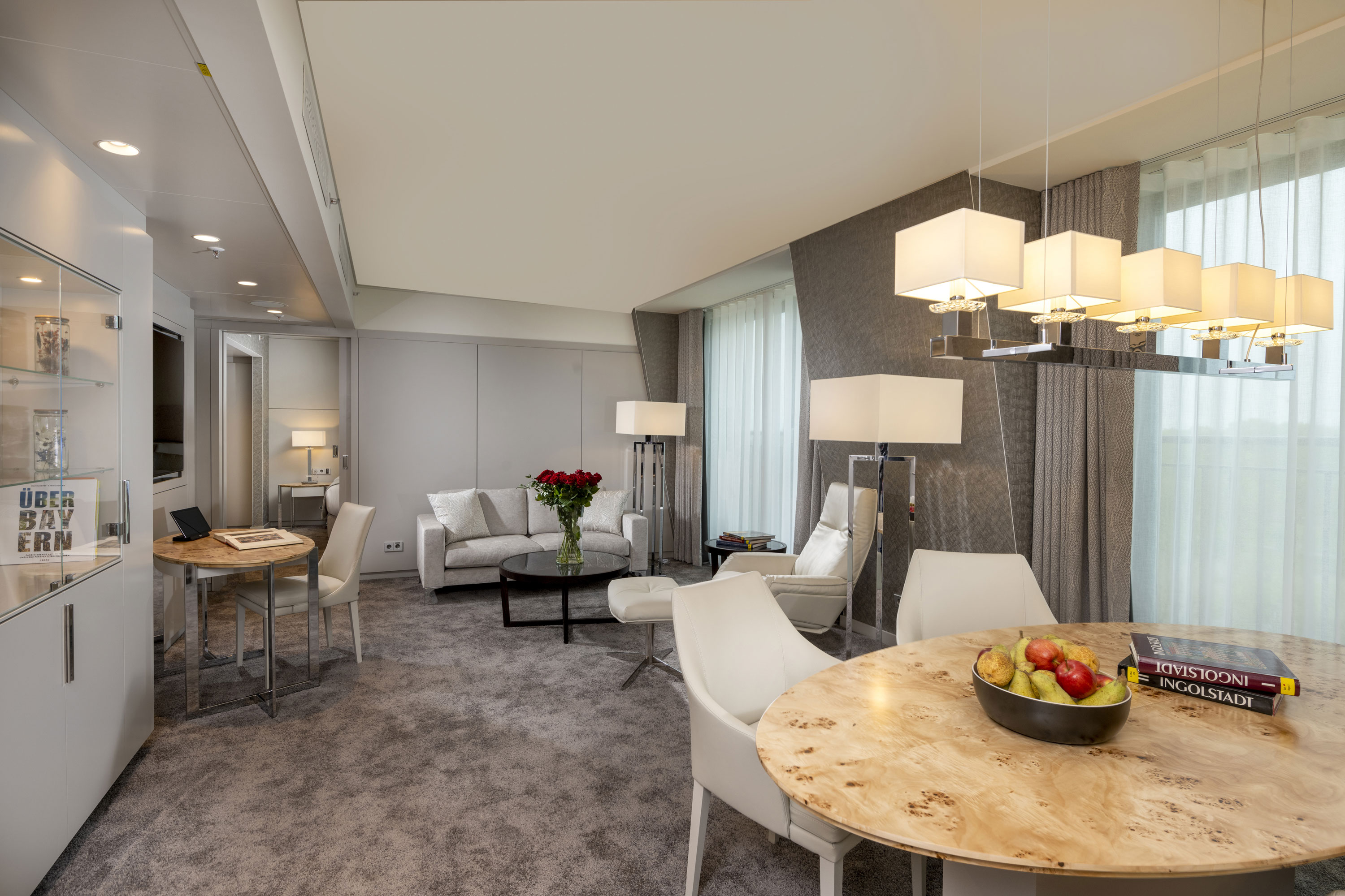 Hochwertig eingerichtete Suite mit hellen Möbeln, gemütlicher Sitzecke und moderner Beleuchtung im Maritim Hotel Ingolstadt.